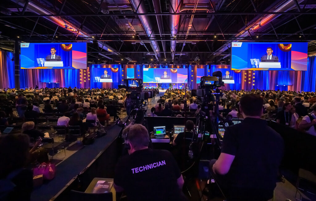 Technicians filming a speech in a busy hall during the EHA2024 Congress.